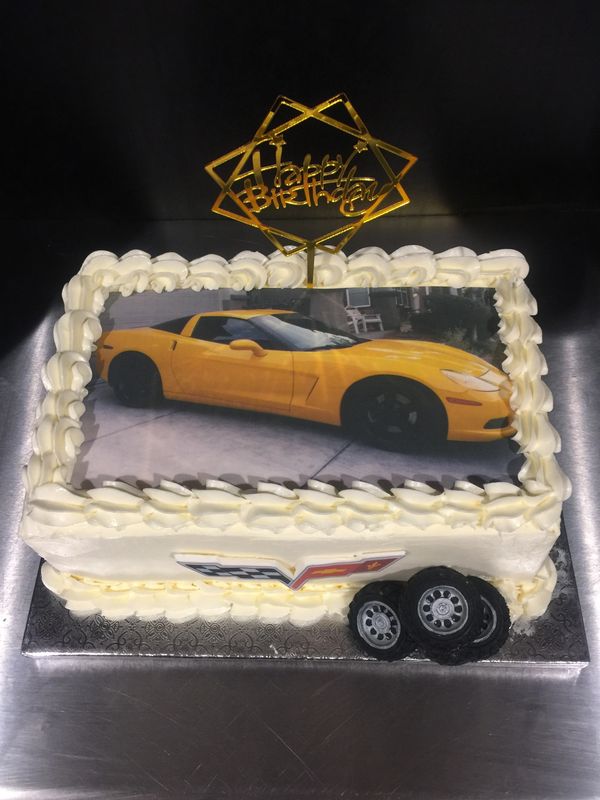 White cake with yellow corvette on top and tires on side with corvette logo