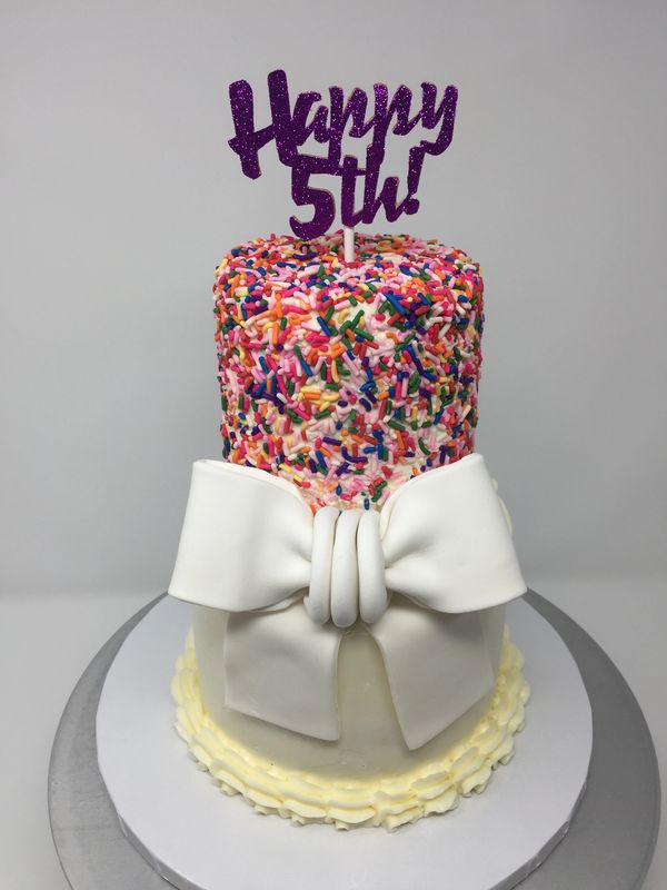 2 tier white cake with white bow, sprinkles on top tier