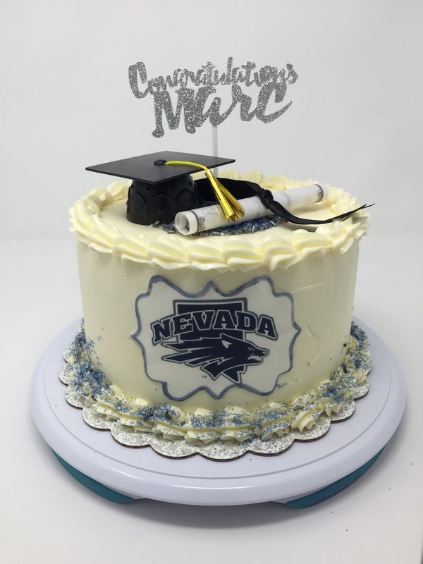 white cake with Nevada Wolfpack logo and graduation cap and diploma o