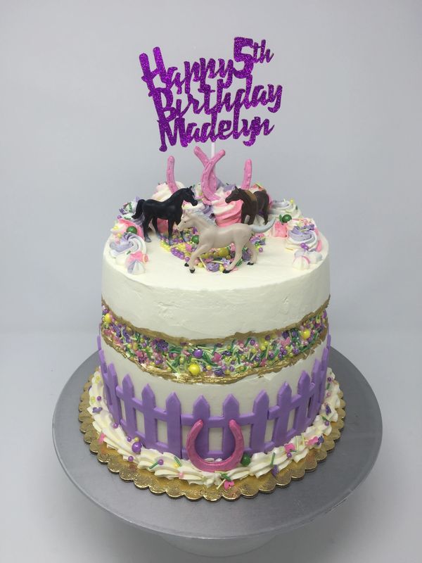 white fault line cake with purple fence going around the cake with 3 horses on top
