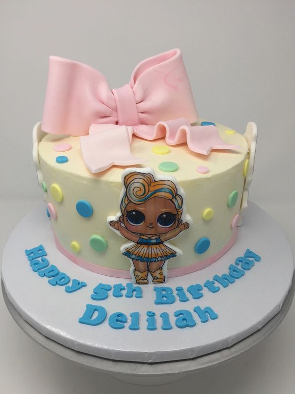 white cake with pastel polka dots, pick bow and cartoon girl