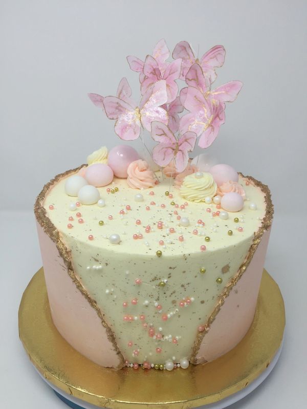 White and pink cake with pink butterflies flying off cake.