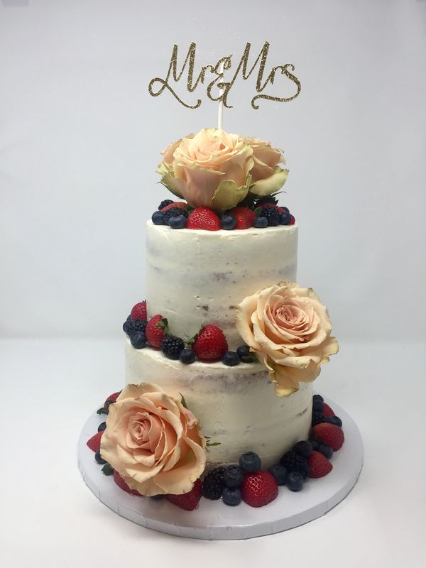 Two tier naked cake with berries and frish flower decorations.