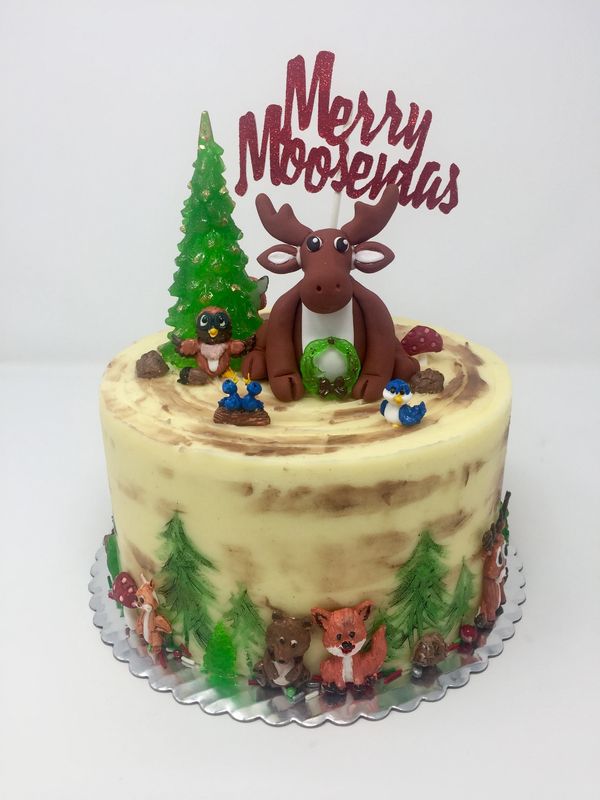 Cream cake with moose on top with sugar pine tree, forest animals and hand painted pine trees.