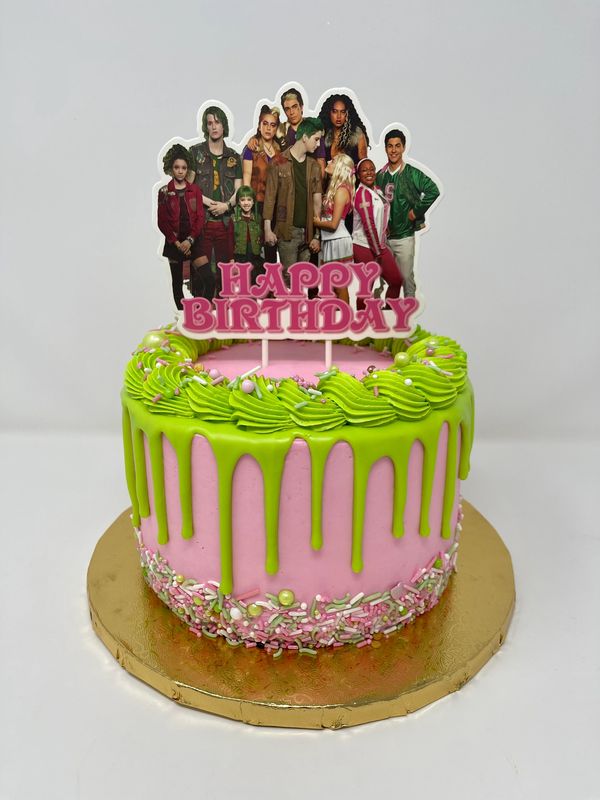 Pink cake with green drip and a group of people on it.