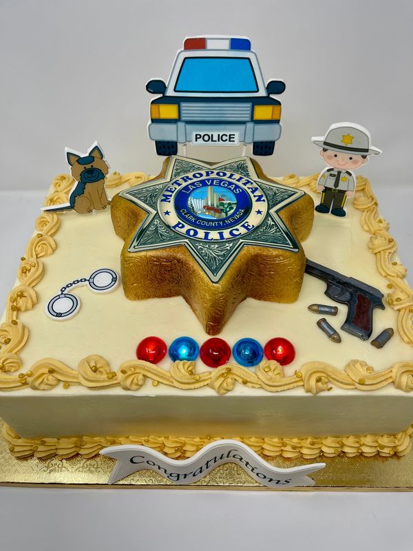 Gold cake with a police badge and policeman, police car, gun, dog and handcuffs.