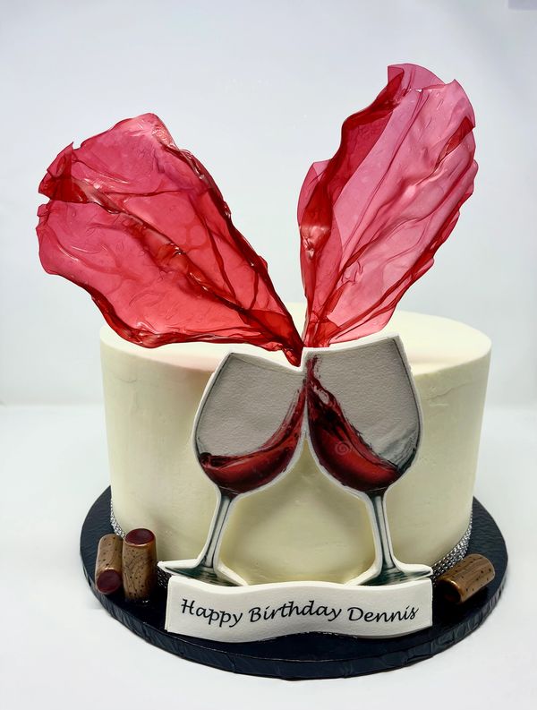 White cake with fondant wine glasses clinking and red wine splashes extending up from the cake.