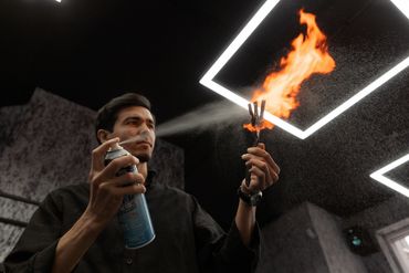 Man spraying aerosol to ignite fire from a tool indoors.