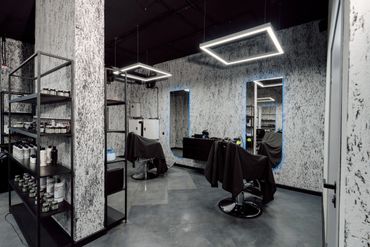 Modern hair salon with monochrome decor and illuminated mirrors.