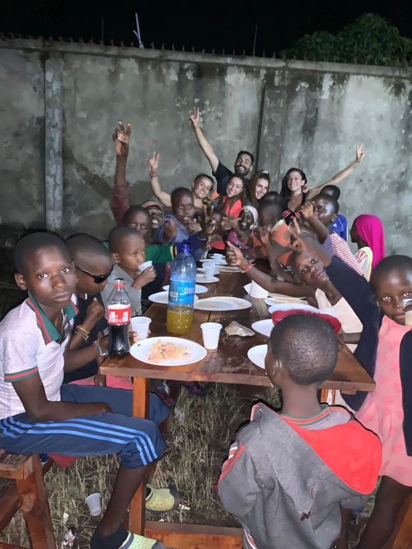 Grupo de adultos y niños sentados en una mesa para comer.
