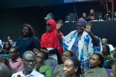 Women and men gathered in an indoor event, some smiling and clapping.