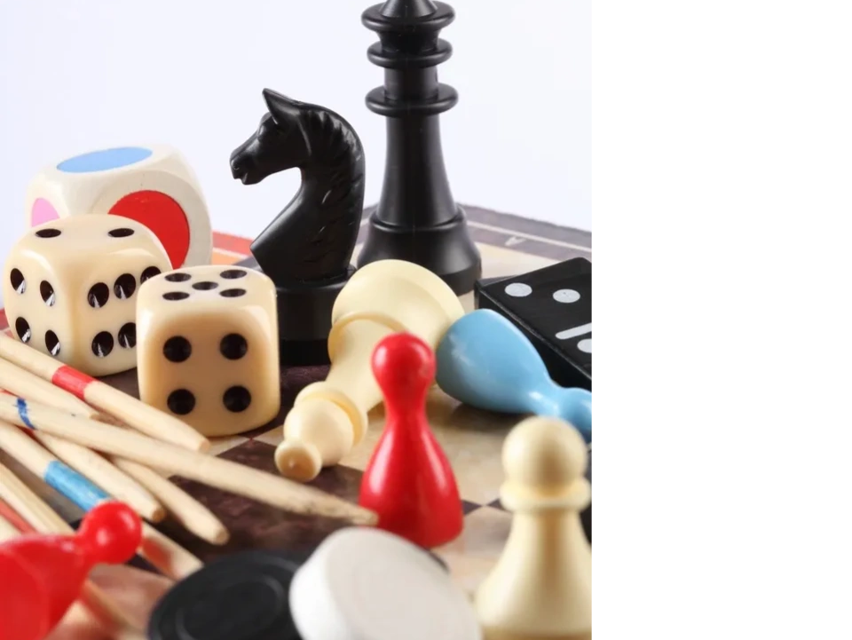 collection of dice, chess pieces, playing pieces and cribbage stakes for game themed book series