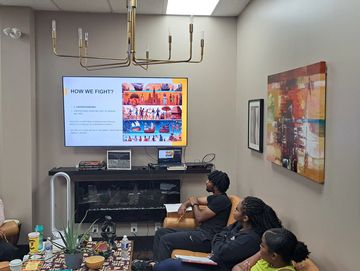 Group watching a presentation on a TV in a living room.