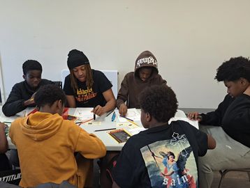 A group of young people engaged in drawing and coloring together at a table.