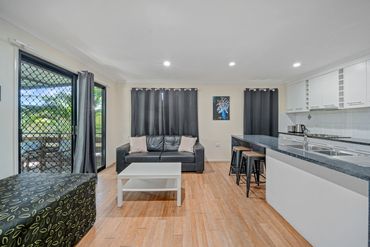 Modern open-plan living area with black leather sofa and kitchen island.