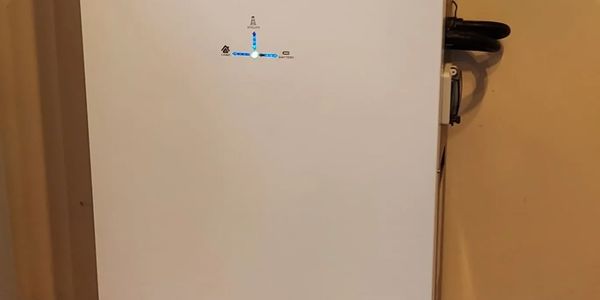 White appliance with blue indicator light on beige wall.