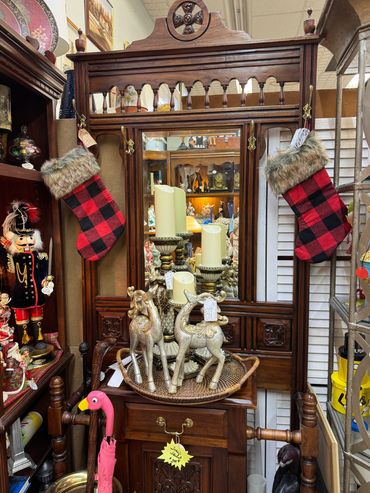 Antique wooden hall tree with buffalo plaid Christmas stockings and decorative items.