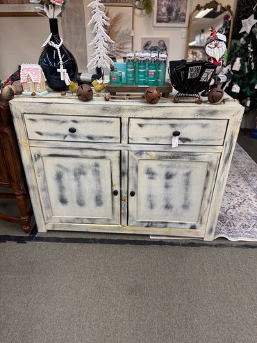 Rustic distressed wooden cabinet with decorative items on top.