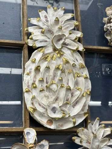 Pineapple-shaped art made from oyster shells with gold-tipped edges.
