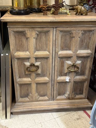 Rustic wooden cabinet with decorative brass handles and vintage items on top.