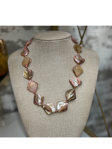 Elegant necklace with square iridescent beads on a beige display bust.