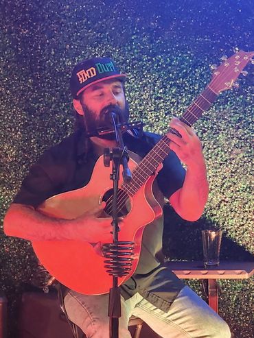 Man playing guitar and harmonica, singing into microphone.