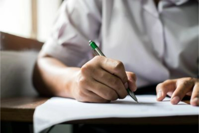 Person writing on paper with a pen.