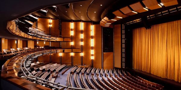 A large, elegant theater with golden curtains and tiered seating.