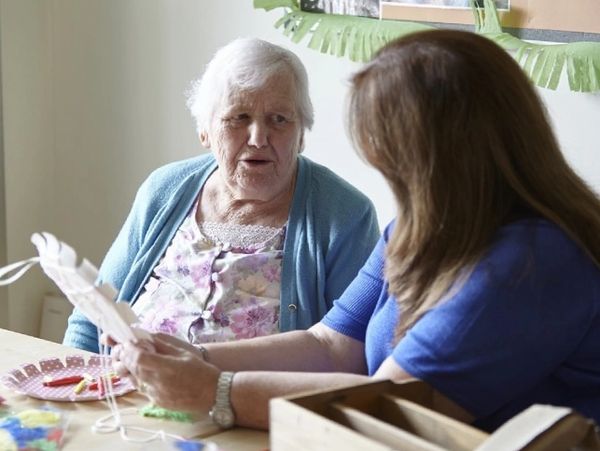 Caregiver and senior woman doing craft together.