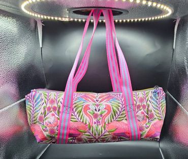 Colorful bag with pink flamingo and floral design under ring light.