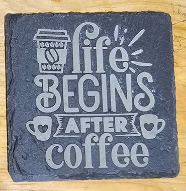 Stone plaque saying life begins after coffee with coffee cup icons.