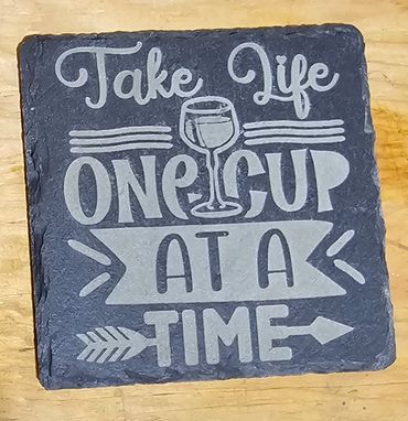 Slate coaster with the phrase 'Take Life One Cup At A Time' and a wine glass illustration.