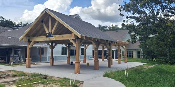 Wooden pavilion with a shingled roof in a backyard under construction.