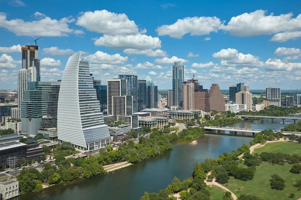 City skyline with river and parks under a blue sky.