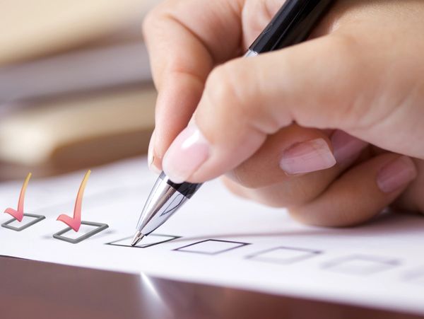 Hand marking checkboxes with a pen on paper.