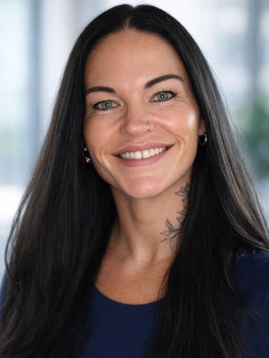 Smiling woman with long dark hair and a nose ring in a professional setting.
