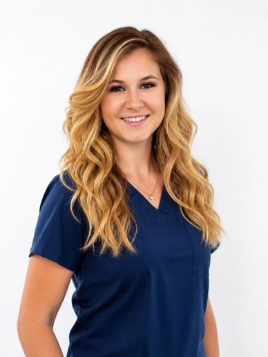 Smiling woman with long blonde hair wearing navy blue scrubs.