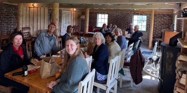 Group of people gathered around a long wooden table indoors.