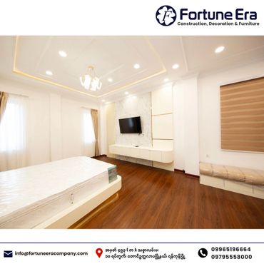 Modern bedroom with wooden flooring, white walls, and a wall-mounted TV.