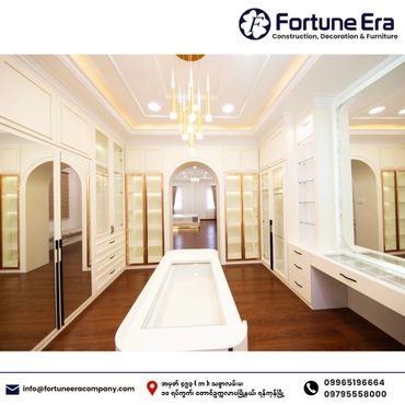Luxurious walk-in closet with elegant lighting and white cabinetry.