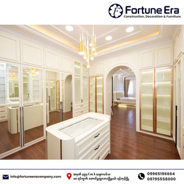 Elegant walk-in closet with white cabinetry and warm wooden flooring.