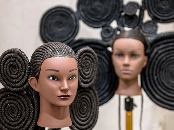 Mannequin heads with intricate coiled hairstyles on display.