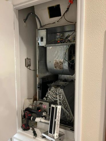 Open HVAC unit with visible components and tools.