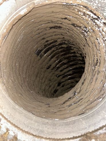 Inside view of a dusty metal pipe with significant buildup.