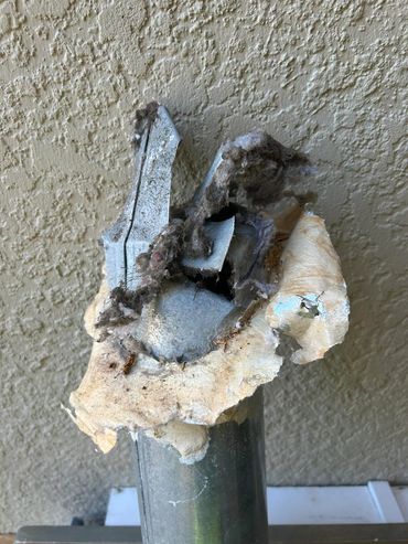 Damaged metal pipe with insulation and debris.