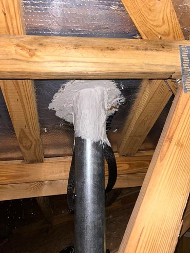 Metal pipe sealed with white plaster in attic.