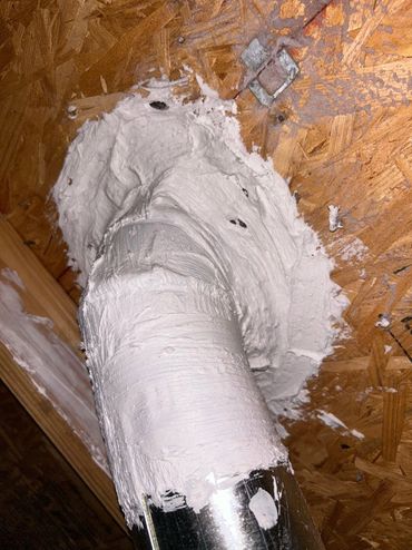 Metal pipe sealed with white caulk on wooden ceiling.