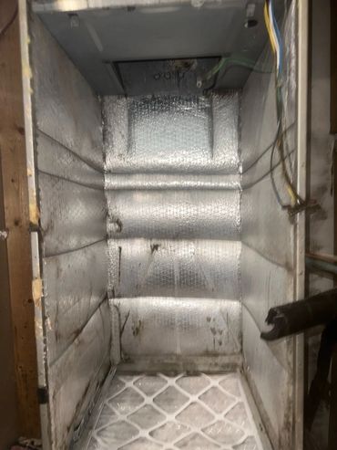 Dirty, insulated HVAC duct with filter at the bottom.