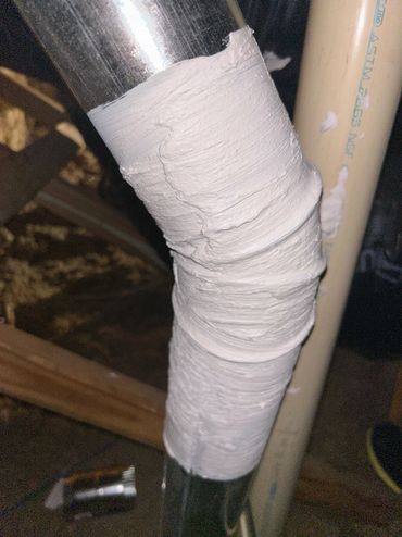A pipe joint wrapped in white tape or sealant.