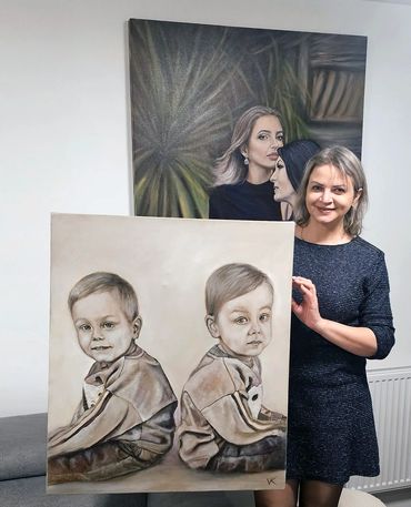Woman proudly holding a detailed portrait of two young boys sitting back-to-back.